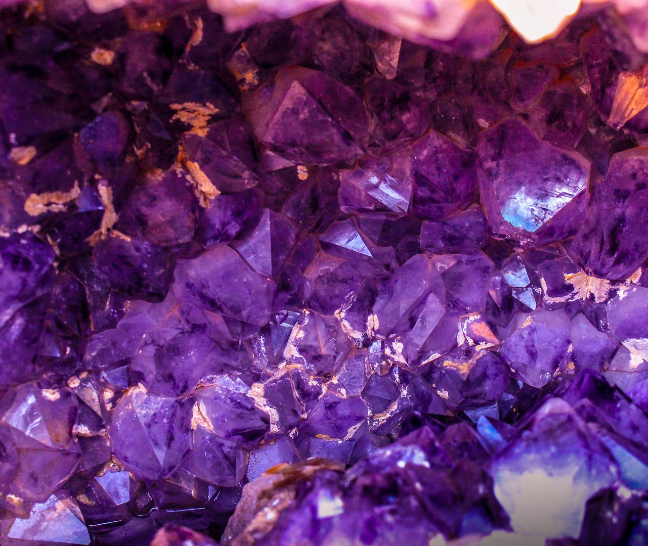 Macro close-up of deep purple amethyst crystal points showing natural geometric facets and internal fractures.